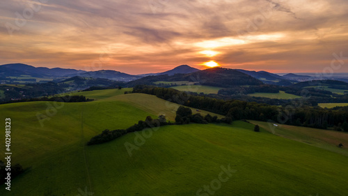 Aerial view of colorful clouds and Ondrejnik peak lying on the horizon during sunset.