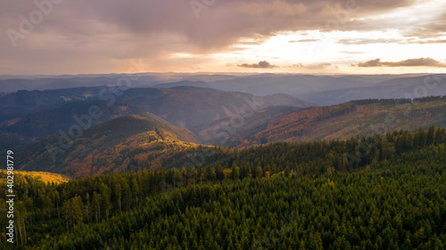 Aerial view of the top of Lysa hill and its surroundings full of trees and views of the surrounding mountains during sunset. © Lukas