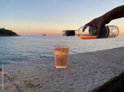 Rovinj Istrien Kroatien Adria Mittelmeer - Flasche Rose Wein wird im Sonnenuntergang auf einem Stein Tisch ausgeschenkt