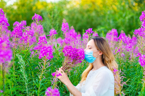 Photography A girl in a medical mask sniffs a bouquet of purple flowers in her hands