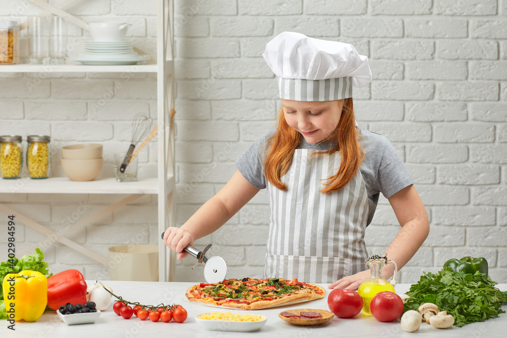 cute little girl in chef hat and an apron cutting pizza at kitchen cute little girl in chef hat and an apron cutting pizza at kitchen