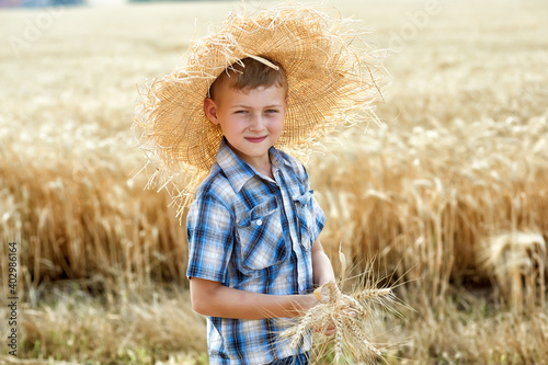The child is resting in nature. Portrait of a boy in a straw hat by a field with wheat. Lifestyle. Happy childhood.