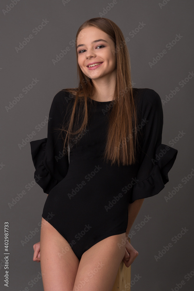 beautiful girl teenager in a stylish black bodysuit posing in the studio on a gray background beautiful girl teenager in a stylish black bodysuit posing in the studio on a gray background