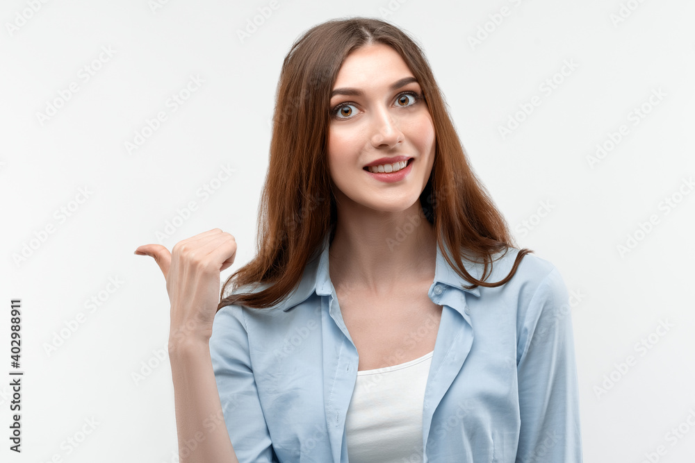 Beautiful girl, pointing and showing with thumb to the side with happy face, smiling. Presenting your product Beautiful girl, pointing and showing with thumb to the side with happy face, smiling. Presenting your product
