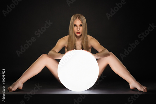 Fotografija beautiful blonde girl posing wide spread her legs behind a large glowing white b