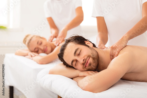 Spouses Receiving Neck And Back Massage Lying At Spa
