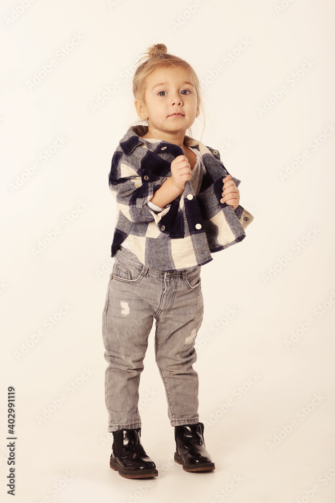 cute little blond baby girl in black boots, jeans, checkered shirt with copy space isolated on white cute little blond baby girl in black boots, jeans, checkered shirt with copy space isolated on white
