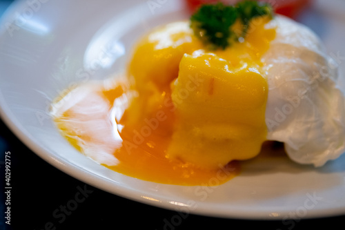 Close up of eggs benedict with liquid egg yolk running out.