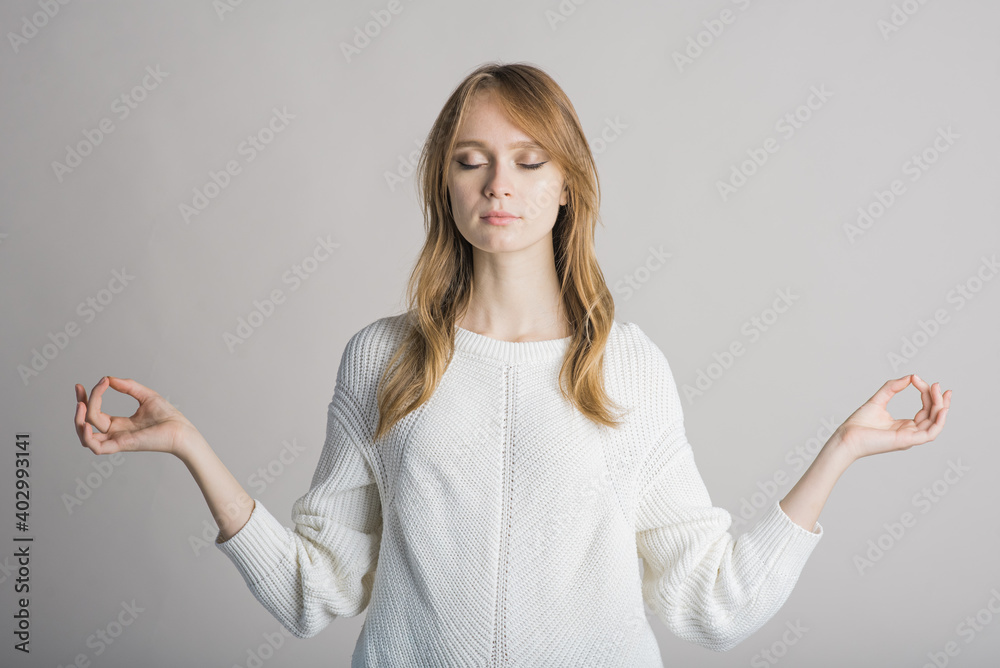 Portrait of a stylish and calm girl on a white background in the studio in the lotus position Portrait of a stylish and calm girl on a white background in the studio in the lotus position