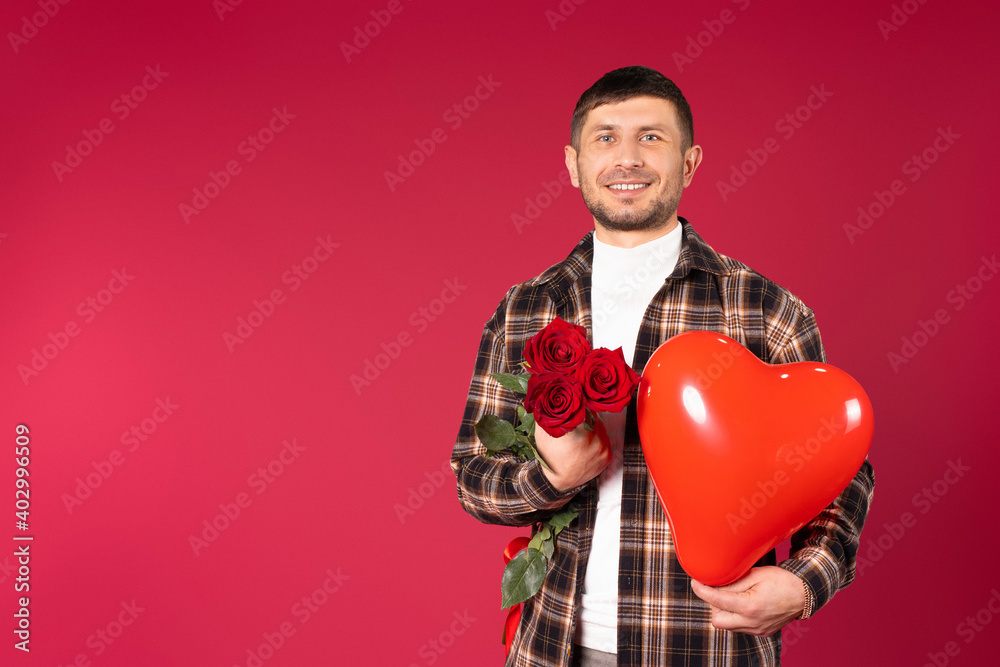 Man with a bouquet of red roses and a red heart-shaped balloon on a red background with side space. Cupidon on St. Valentiines Day Man with a bouquet of red roses and a red heart-shaped balloon on a red background with side space. Cupidon on St. Valentiines Day