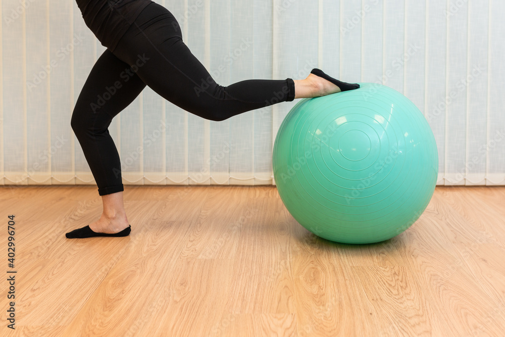 Naklejka premium girl pilates trainer does split fitball posture in fitness center