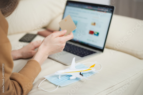 Young woman holding credit card and using laptop computer. Online shopping, e-commerce, internet banking, spending money, air tickets, working from home concept