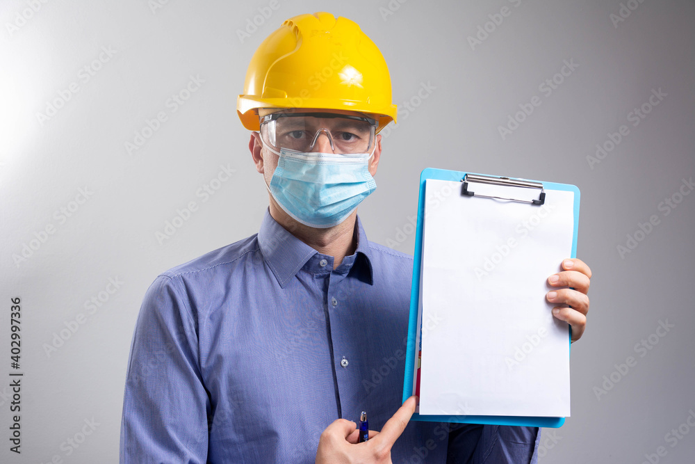 Worker man wearing face mask and protective hard hat shows health procedures during pandemic. Worker man wearing face mask and protective hard hat shows health procedures during pandemic.
