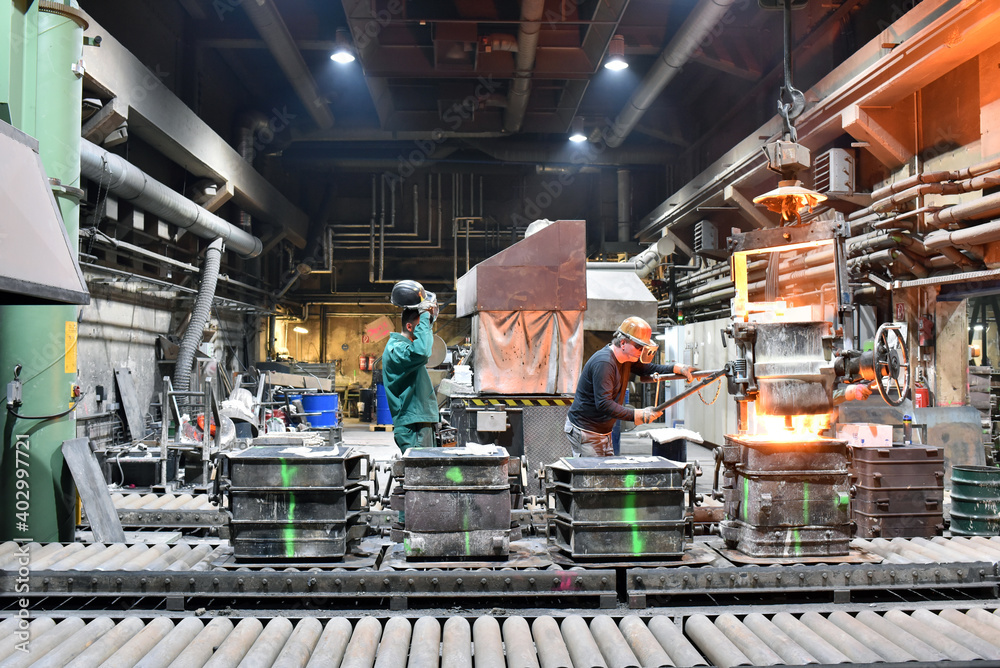 Fototapeta premium group of workes in a foundry - production in steelworks - industrial building inside