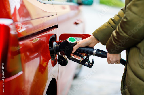 Close-up of hands of woman at self-service gas station, hold fuel nozzle and refuel the car with petrol, diesel, gas. Close up of filling auto with gasoline or benzine. Self service gas pump