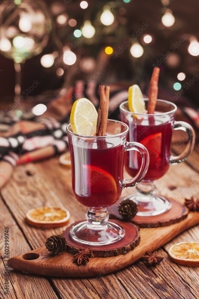 Mulled wine with cinnamon sticks and orange on the background of a christmas garland Mulled wine with cinnamon sticks and orange on the background of a christmas garland