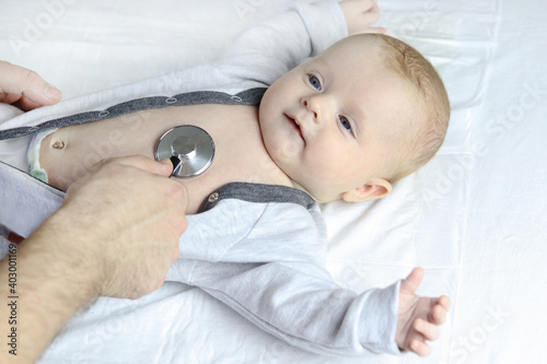 A specialist pediatrician conducts a screening examination of the baby's body, listens to the heart with a statoscope, top view. Copy space - concept of child health and disease prevention, pediatrics