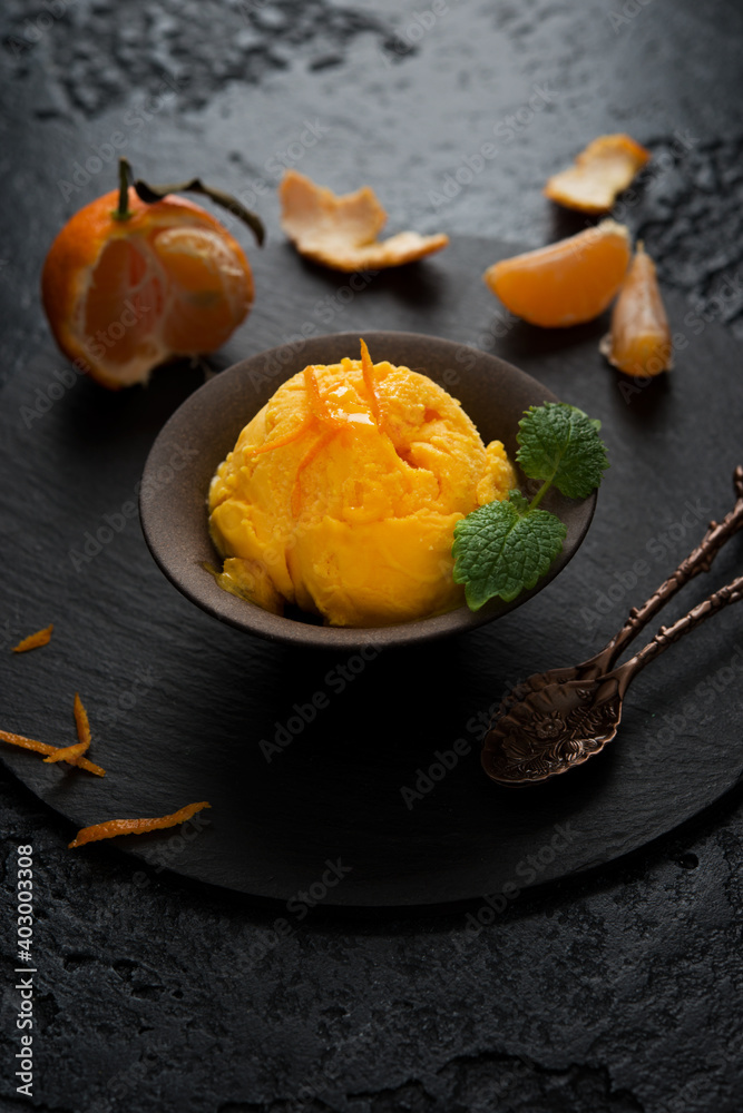 Tangerine ice cream in a cup on a black background Tangerine ice cream in a cup on a black background