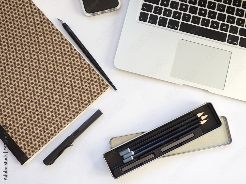 Modern workplace with laptop, cellphone, notebook, quills, pens and pencil for home office. Work from home. Concept for artist or creative work on white table. Modern workplace with laptop, cellphone, notebook, quills, pens and pencil for home office. Work from home. Concept for artist or creative work on white table.