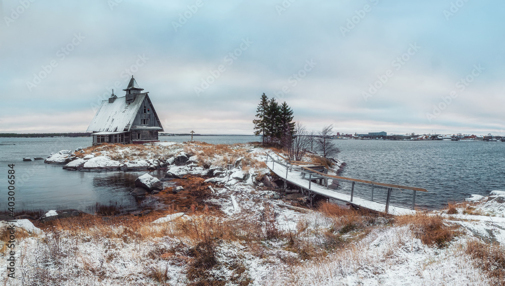 Snowy winter landscape with authentic house on the shore in the Russian village Rabocheostrovsk.
