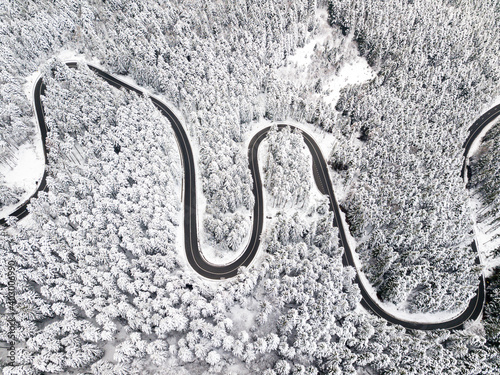 Winding road among a snowy forest, from high mountain pass, winter weather. Aerial view by drone. Romania © Rafaila Gheorghita