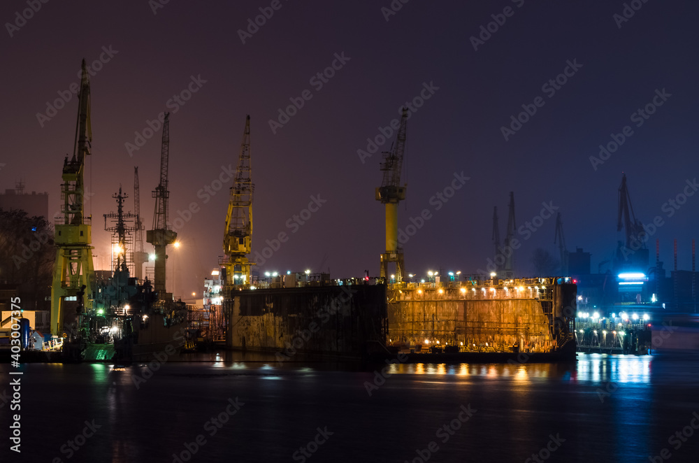 SHIPYARD - A floating repair dock and port cranes on the wharves

