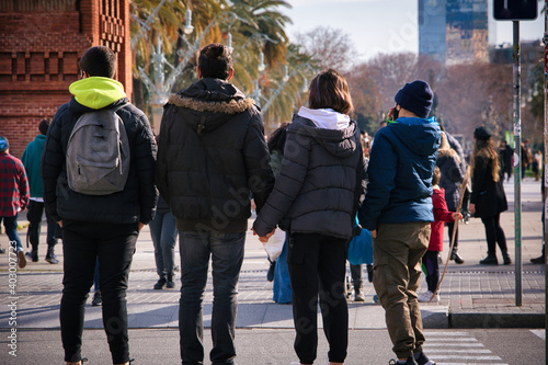  Photo of a family in the middle of the day waiting for the green light to cross to the other side.