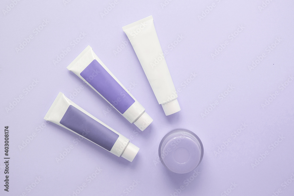three tubes with cosmetic creams, one jar with cosmetics on a lilac background, beauty concept three tubes with cosmetic creams, one jar with cosmetics on a lilac background, beauty concept