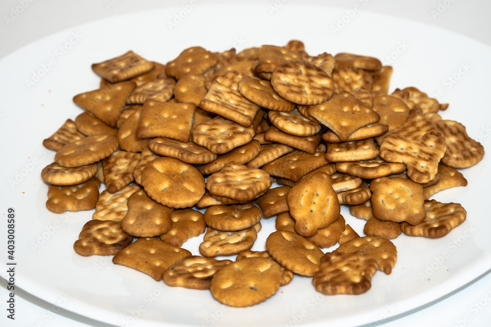 Salty biscuit cracker on a white plate on a white background Salty biscuit cracker on a white plate on a white background