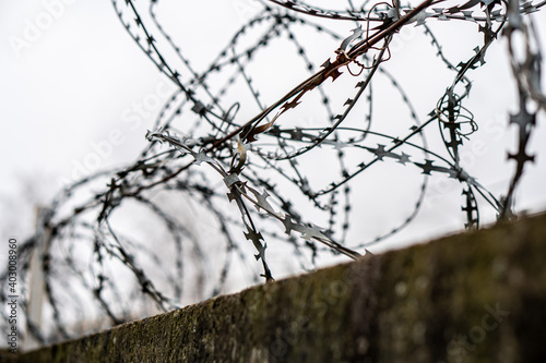 Barbed wire on a concrete fence against a grey sky