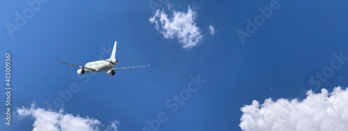 Passenger airplane as seen from ground flying in deep blue cloudy sky © aerial-drone