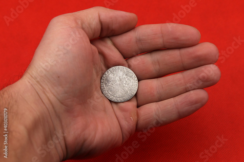 Medieval european silver coin in hand on red background