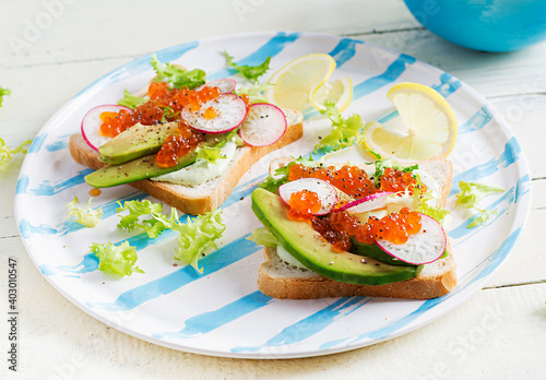 Sandwiches with salmon red caviar with sliced avocado and radish. Sandwich for lunch. Premium food