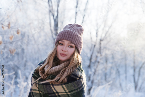 beautiful young woman in plaid blanket smiles and laughs on a winter walk