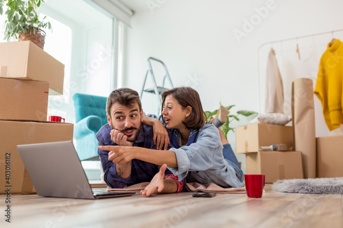 Couple surfing the Net using laptop computer while moving in together