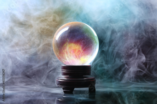 Crystal ball of fortune teller in smoke on table