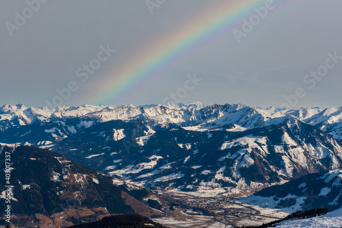 Snowy mountain peaks in the Zell am See area of Austria. You can see Zell am See and the sky on which there is a rainbow.