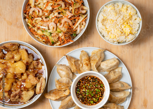 Colorful palette of asian take away food - prawn salad, sweet crunchy chicken, rice and fried dumplings on wooden background