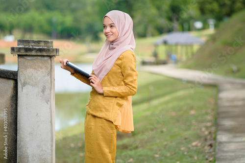 Asian muslim student woman with traditional dress wearing medical face mask at le lake