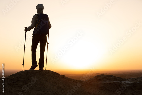 Successful woman hiker enjoy the view on sand desert in the sunset