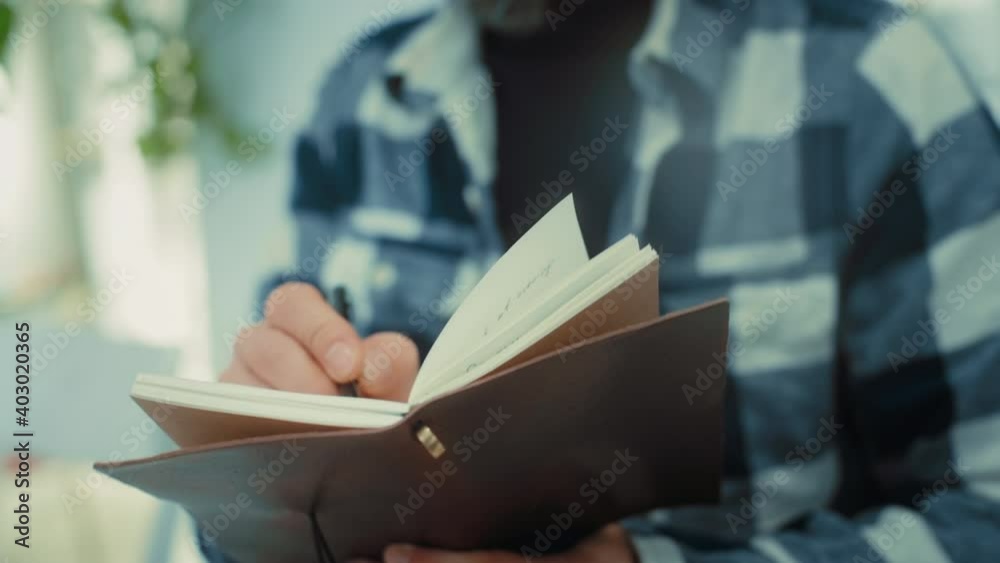 Man write down text notes with pen in leather paper notebook. Learning new skills, or writing down diary during lecture or class. Old fashioned planning skills. Write with pen in vintage notebook