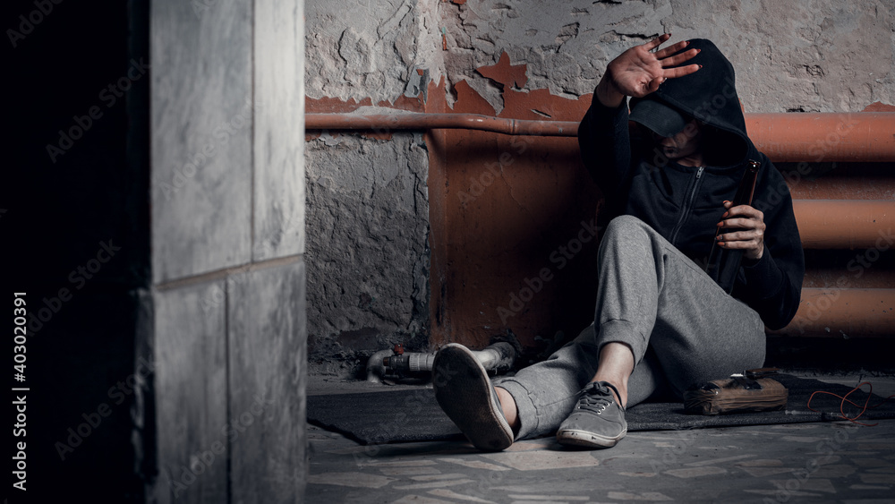 The concept of drug addiction and homelessness. A depressed and hopeless woman sits after using drugs and alcohol in an abandoned house The concept of drug addiction and homelessness. A depressed and hopeless woman sits after using drugs and alcohol in an abandoned house