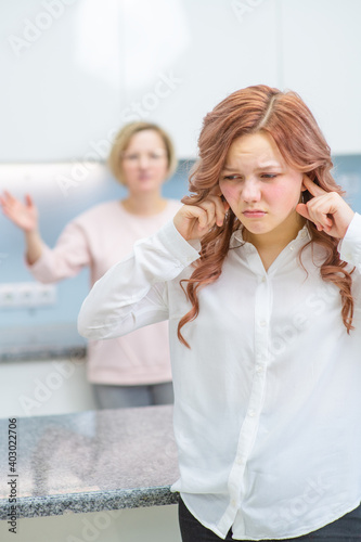 The teenage girl closed her eyes and closed her ears. Her mother in the background chastises her. Relationship problems, puberty