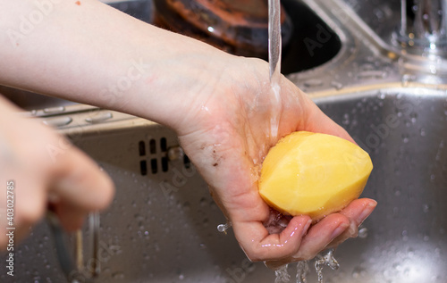 girl peels potatoes at home in the sink