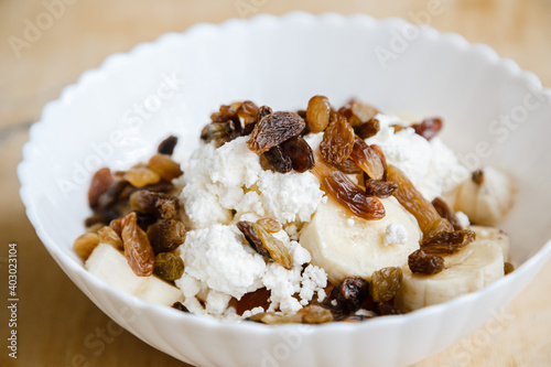 White plate with cottage cheese, with raisins, with a banana photo