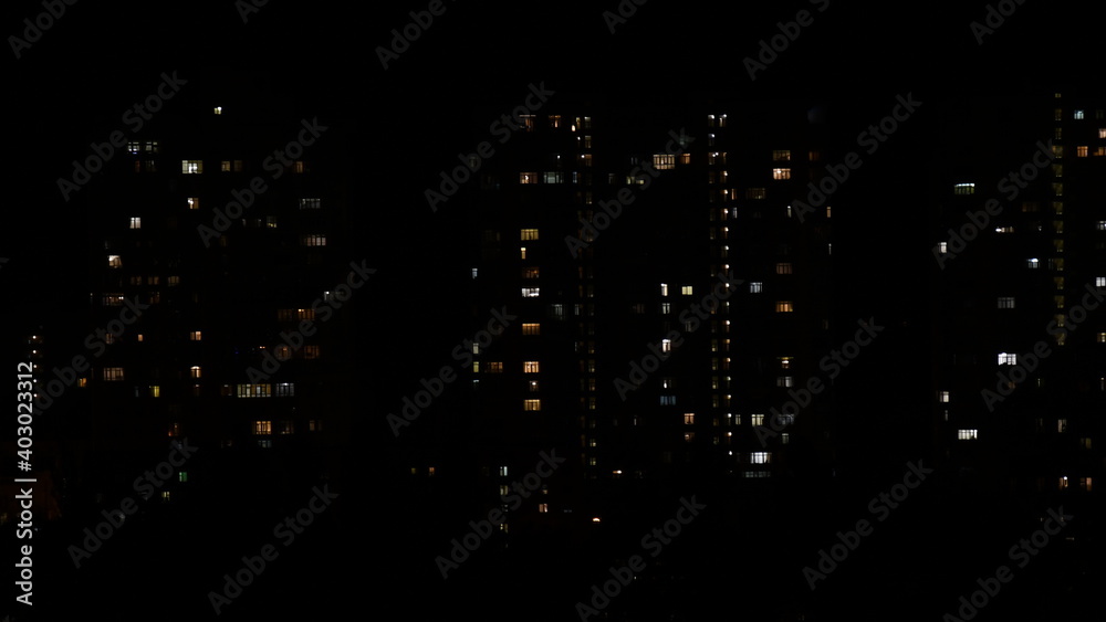 Night city view with lights in windows of multistory buildings in darkness. Defocus lights of residential house windows. Urban abstraction in big city Night city view with lights in windows of multistory buildings in darkness. Defocus lights of residential house windows. Urban abstraction in big city