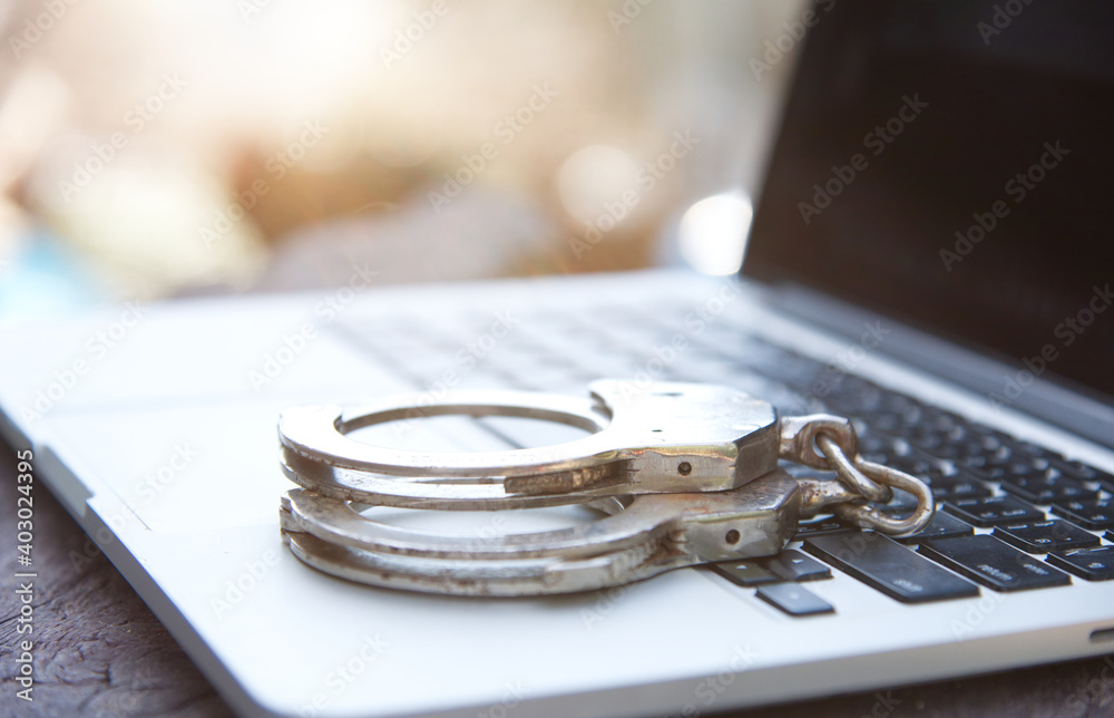 Cyber crime concept with Police handcuff on notebook keyboard Cyber crime concept with Police handcuff on notebook keyboard