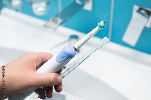 Electric toothbrush versus manual toothbrush in hand. Oral care and prevention concept.