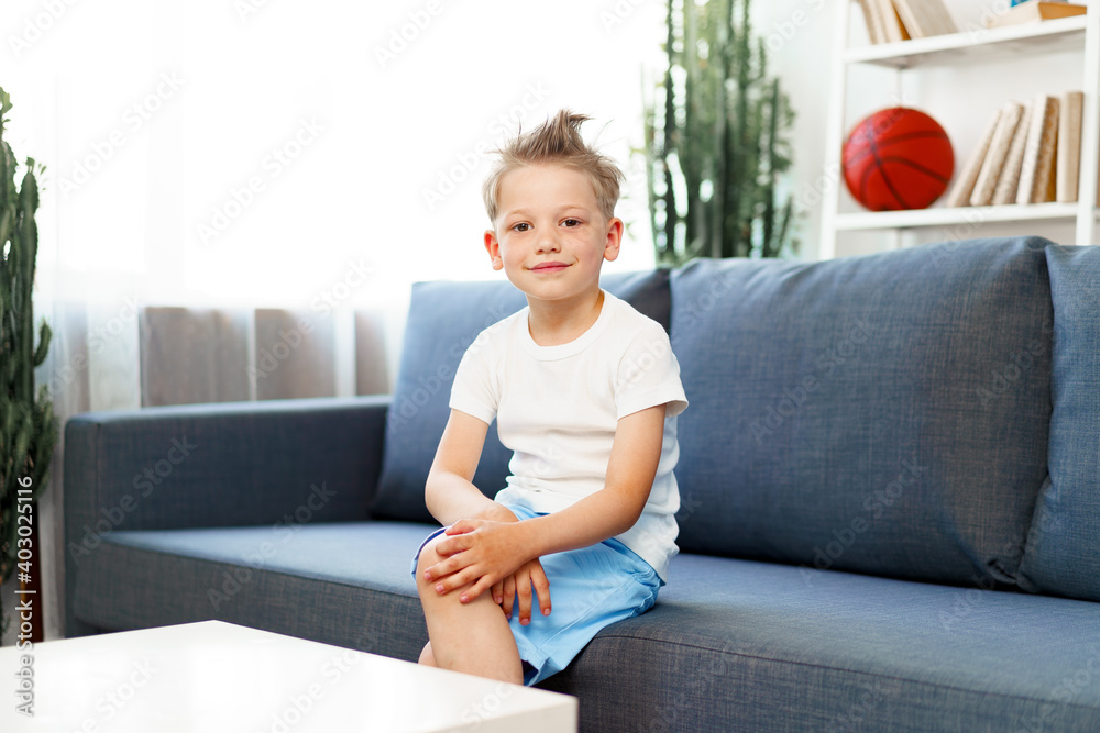 Cute little boy sitting on couch at home, looking at camera Cute little boy sitting on couch at home, looking at camera