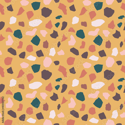 Seamless terrazzo pattern in modern muted colors. Multicolor stone tiles on mustard background. 